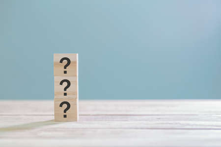 Wooden cube block with sign question mark symbol on wood table with with copy space