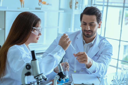 Attractive scientist medical worker with sample test tube at laboratory , doing a analysis in a...