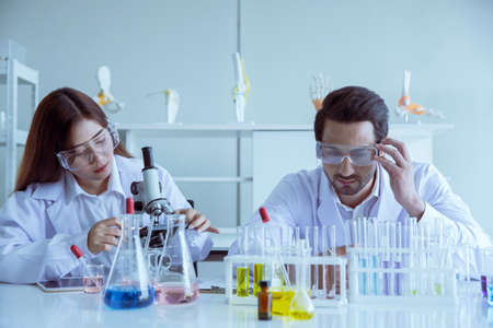 Attractive scientist medical worker with sample test COVID-19 or coronavirus tube at laboratory , doing a analysis in a laboratory doing research to create a vaccine and developmentの写真素材
