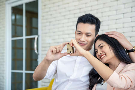 Happy young loving couple talking to their real estate agent with smile looking at house , Planning...
