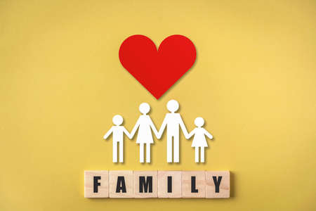 Wooden cube with family text , Family figures with red heart on yellow background , Medical care and health insurance concept.の写真素材