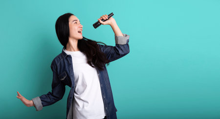 Young beautiful asian stylish woman singing karaoke isolated on blue background , Asia woman singing karaokeの写真素材