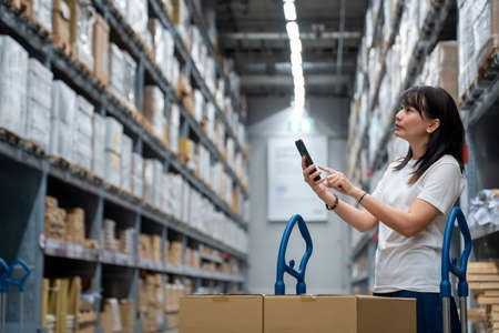 Portrait of young smart asian female shopping new lifestyle , Smiling asia woman standing between of stock product inventory on shelf compare productsの写真素材