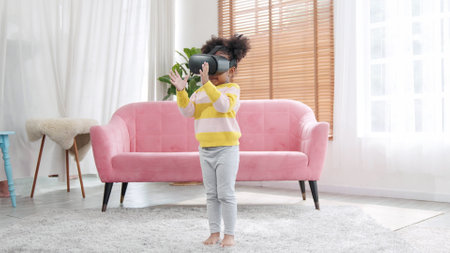 Portrait of enjoy happy kids using VR metaverse gaming technology in living room at home. Child smiling and having fun using glasses of technology virtual reality headset playing sport gamingの写真素材