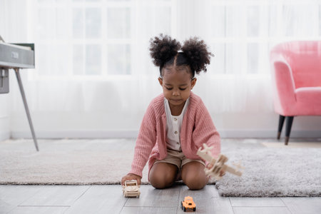 Creative game, imagination child and toy. Cute toddler girl playing with wooden block bricks toy. Cute funny preschooler little girl in modern living room playing with construction toy blocks buildingの写真素材