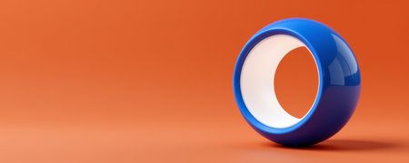 A glossy blue circular object with hollow center on orange background, showcasing innovative shape and smooth reflective surfaceの素材