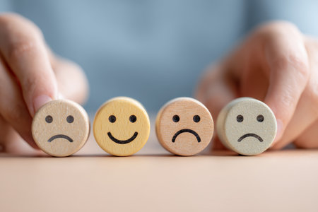 Four wooden circles with different facial expressions, including happy and sad, represent emotion, mood, and mental health conceptsの素材