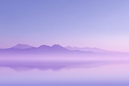 Purple misty mountain range reflected on calm lake at sunrise with soft pastel sky and serene atmosphereの素材
