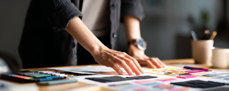 Creative planning workspace hand detail designer desk color swatch paper layout office table modern studio soft light focus calm moodの素材