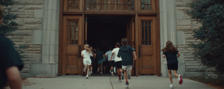 Children running into school building with wooden doors and stone walls on sunny day, showing energy and excitementの素材