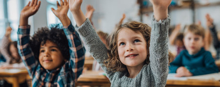 Children raising hands in classroom learning happily with focus and curiosityの素材