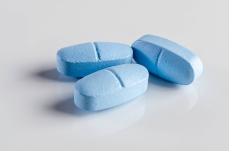 Few blue pills on reflective background.の写真素材