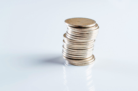 Coin stack on reflective white background.