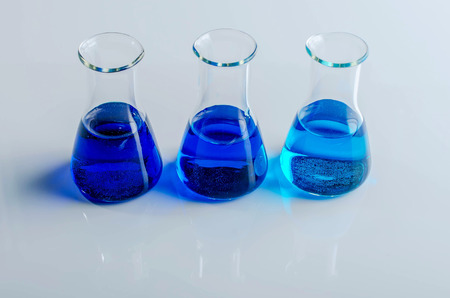 Three titration flasks filled with blue liquid. Laboratory glassware.