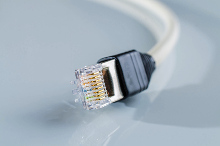Network cable with RJ45 connector on reflective background.