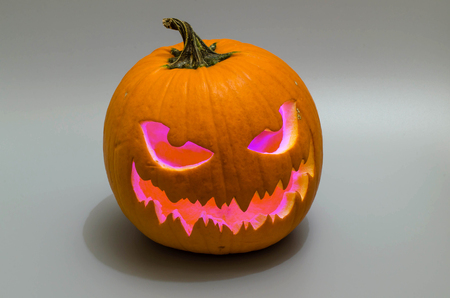Jack-o 'lantern with purple light on gray backround. Halloween background.の写真素材