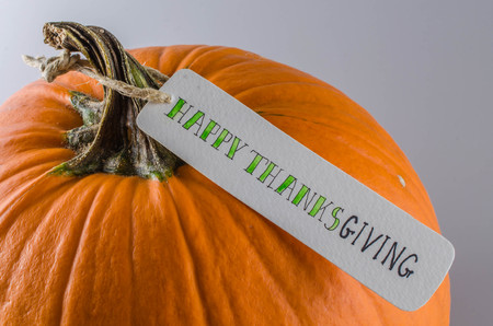 Pumpkin with tag Happy Thanksgiving on a gray background.の写真素材