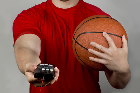 Holding tv romote control and basketball.の写真素材