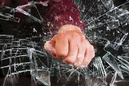 Hand through broken glass window.