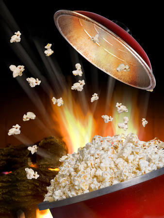 Popping popcorn the old fashion way in a red iron pot.の写真素材