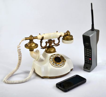 Working smart cell phone and old white rotary telephone.の写真素材