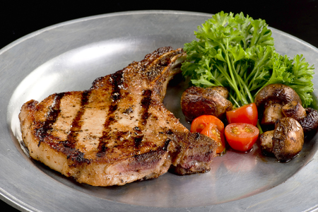 Grilled fresh pork chop with mushrooms and cherry tomatoes.の写真素材