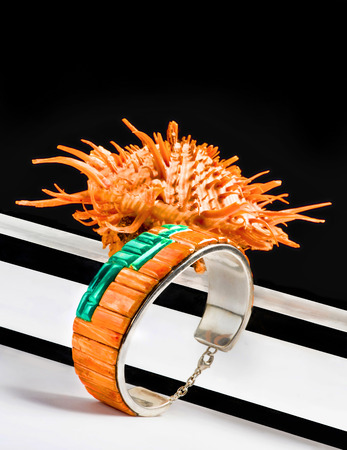 Navajo silver bracelet made from orange spiny oyster with spiny oyster shell in background.
