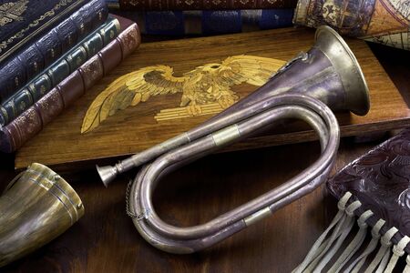 Old antique brass bugle with leather books and wooden eagle.