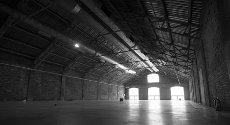 Large empty hangar with light going through the windowsの写真素材