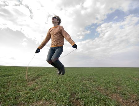 Young man jumping high with a skipping-ropeの写真素材