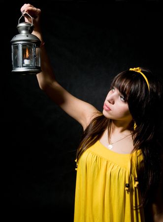 Teenage girl holding lit lantern on black backgroundの写真素材