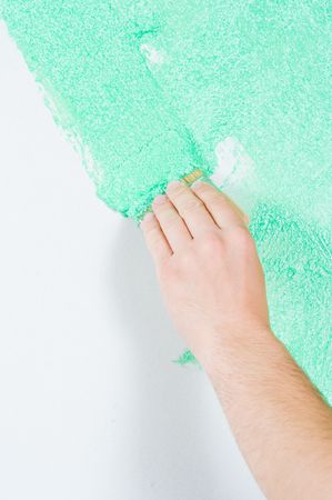 Male hand painting the wall with brush in greenの写真素材