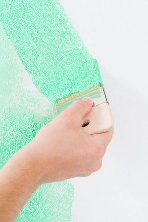 Male hand painting the wall with brush in greenの写真素材