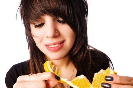 Teenage girl eating orange  isolated on white backgroundの写真素材