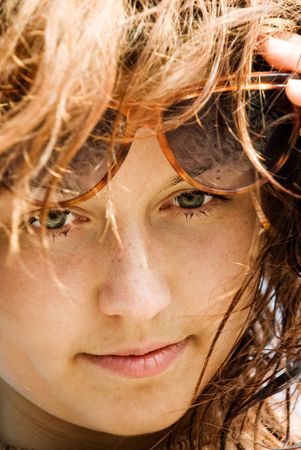 Closeup portrait of a beautiful red-haired girl with sunglasses