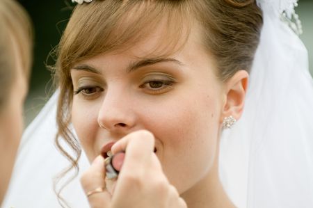 Makeup artist performs a wedding makeup for a bride.の写真素材