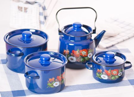 Kitchen utensil set of blue pots and kettle arranged on a tableの写真素材