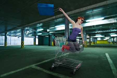 Red girl riding shopping cart at the mall undergroundparkingの写真素材