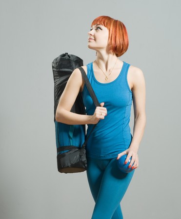 Red-haired fitness girl with yoga mat at the gymの写真素材