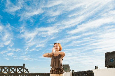 Beautiful young dancer performing yoga-dance outdoors with blue sky and clouds in the backgroundの写真素材