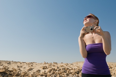 Girl with compact camera taking photos at the desertの写真素材