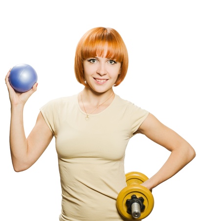 Beautiful redhair woman with fitness ball and dumbbells over whiteの写真素材