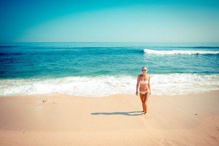 Young slim woman wearing bikini and sunglasses at the ocean beachの写真素材