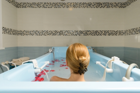 Young woman taking bath with milk and rose petals at spa salonの写真素材