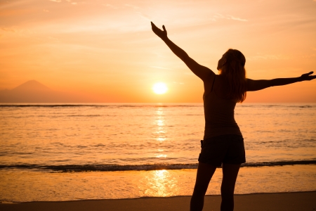 Young woman watching as sun sets over Bali, Pacific Oceanの写真素材