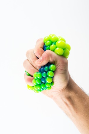 Male hand squeezing stress ball over plain の写真素材
