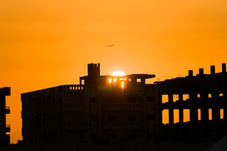 Plane take off at sunset over city ruinsの写真素材