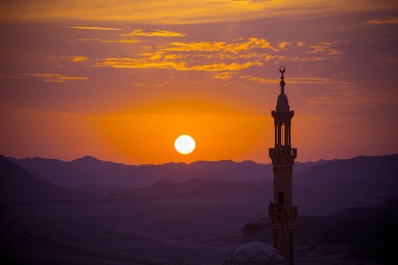 Sunset over desert with muslim mosque in the foreground. Focus on distant mountainsの写真素材