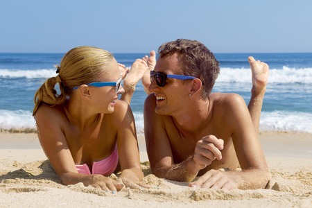 Happy couple having fun on the beach. Summer Vacation. Laughing Family enjoying Nature over Sea Background. Attractive Man and Woman at the Beachの写真素材