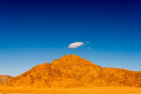 Desert landscape with mountain and single cloudの写真素材
